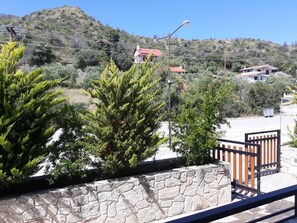 A stone wall with a metal gate, a clear view of a hillside with houses, and a street lamp.