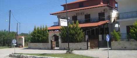 A two-story building with a red-tiled roof, a balcony, and a sign indicating a restaurant.