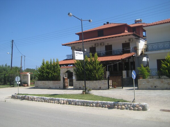 A two-story building with a red-tiled roof, a balcony, and a sign indicating a restaurant.