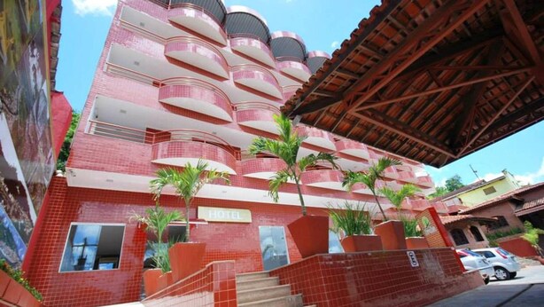 A hotel with multiple balconies, a red tiled facade, and a sign indicating it is a hotel.