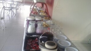 A buffet setup with various food items, a coffee maker, and stacked plates.