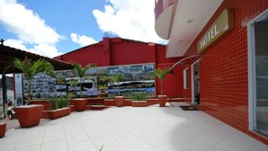 A hotel courtyard with tiled flooring, potted plants, and a mural on the wall.