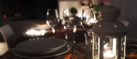 A table set for dining with a lit lantern, clear glassware, and a woven placemat.