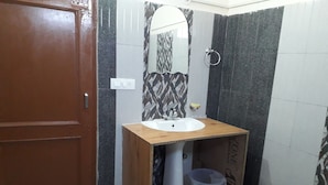 A bathroom with a wooden vanity, a sink, a mirror, a trash bin, and a toilet. - Beyond Stay Tikker Narkanda Cottage (Theog)