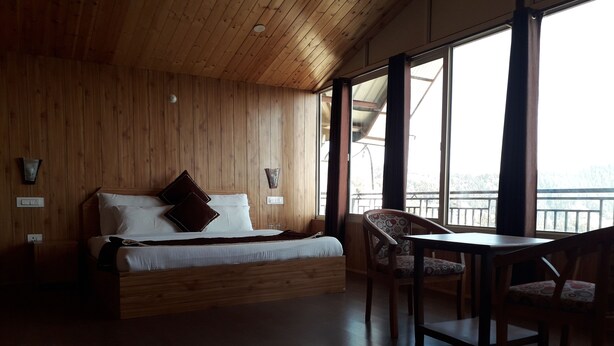 A wooden-paneled room with a bed, a table, and chairs. - Beyond Stay Tikker Narkanda Cottage (Theog)