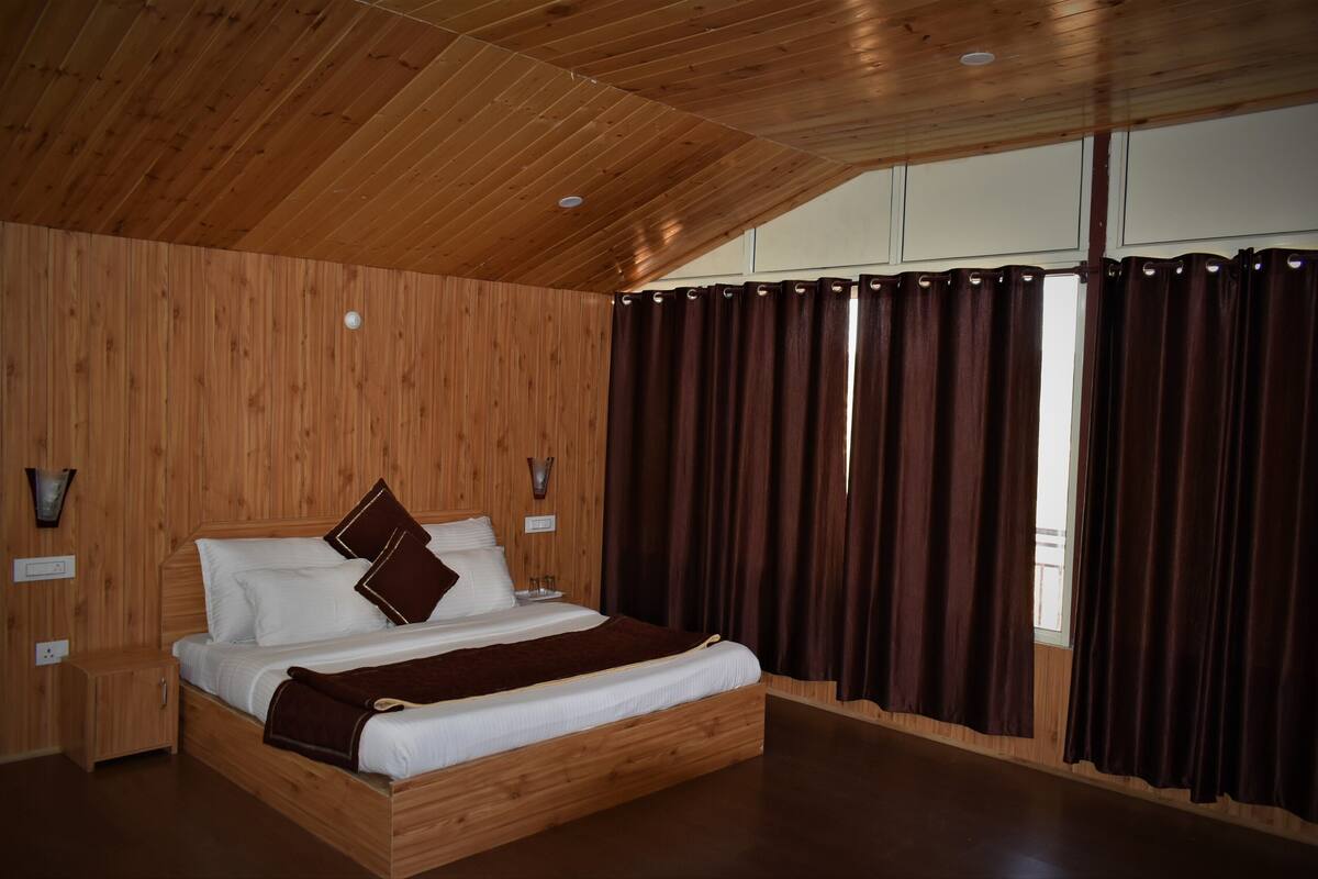 A wooden-paneled bedroom with a bed, curtains, and wall sconces.