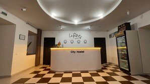 Un comptoir d’accueil avec une enseigne indiquant « City Hostel » et une horloge au-dessus.
