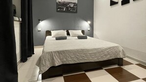 Une chambre à coucher moderne avec un grand lit, un sol à carreaux et une œuvre d’art représentant un paysage urbain accrochée au mur.