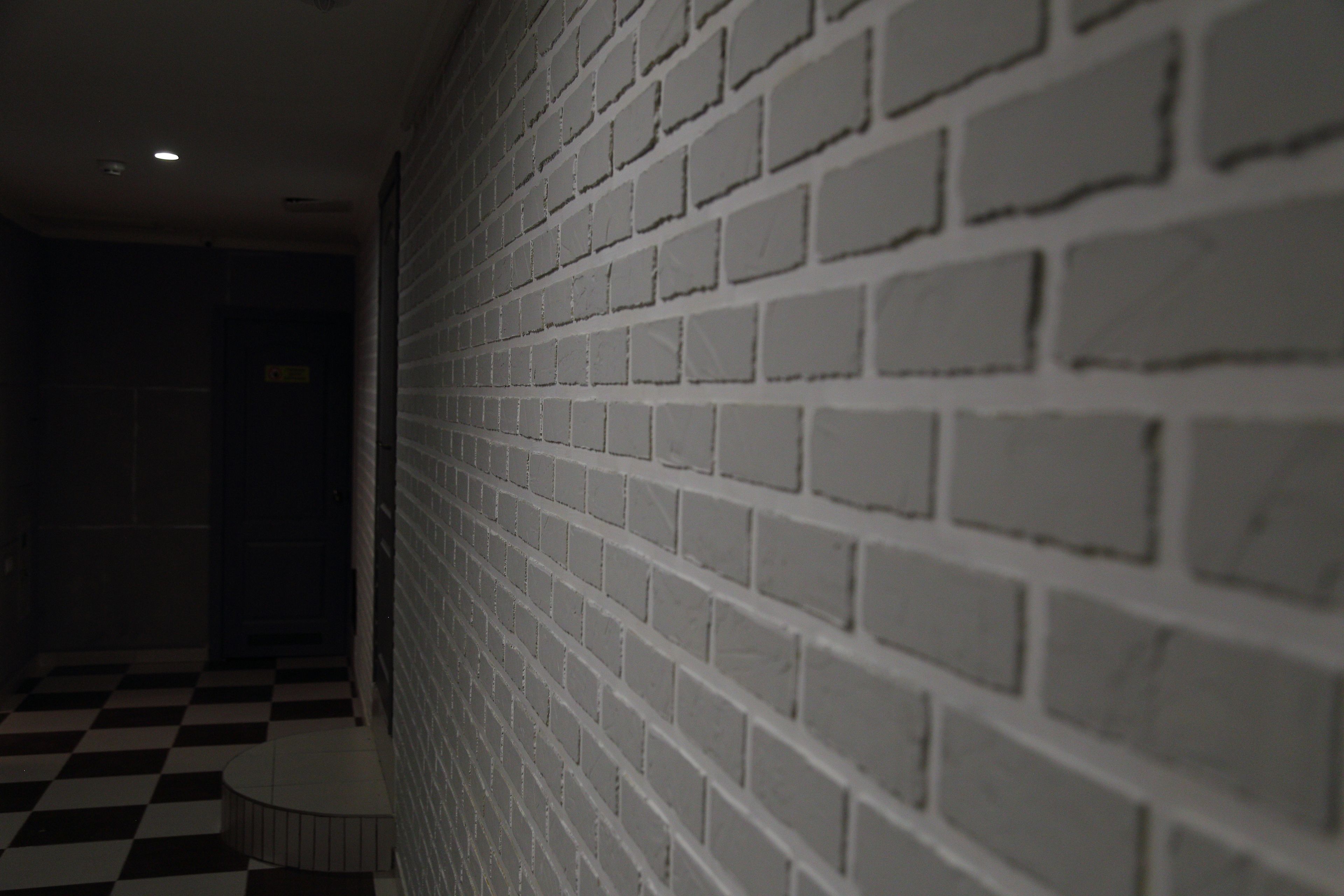 Un pasillo con pared de ladrillo blanco y suelo a cuadros.