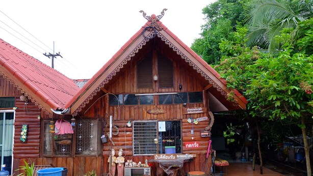 Une maison en bois avec un toit en pente, un balcon et une enseigne.
