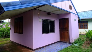 Une petite maison à un seul étage, avec un toit bleu et une façade rose.