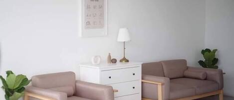 A minimalist living room with two sofas, a white side table, a lamp, and a framed picture on the wall.
