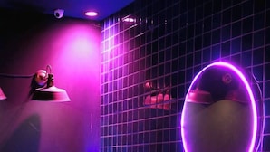 A modern room with a pink sofa, a round neon light, and a grid-patterned wall. - The Zen Hotel Yasothon (Yasothon)