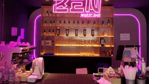 A music bar with a neon sign, shelves of bottles, glasses, and a bar counter with various items. - The Zen Hotel Yasothon (Yasothon)