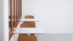 A row of white tables and brown chairs in a room with white walls and a tiled floor. - The Zen Hotel Yasothon (Yasothon)