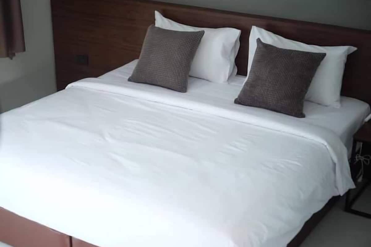 Ein ordentlich bezogenes Bett mit weißer Bettwäsche und zwei grauen Kissen.
