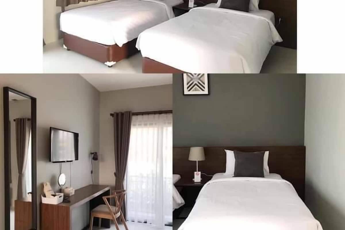 Ein Hotelzimmer mit zwei Betten, einem Schreibtisch, einem Sessel, einem Fernseher und einem Spiegel.