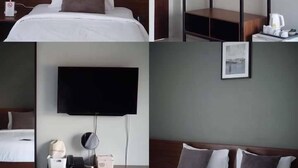 A hotel room with a bed, a TV, a bedside table with a lamp, and a coat rack. - The Zen Hotel Yasothon (Yasothon)