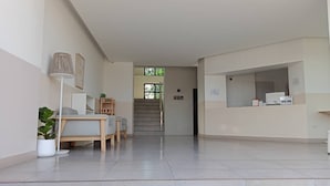 A reception area with a reception desk, a staircase, and a seating area with a table and chairs. - The Zen Hotel Yasothon (Yasothon)
