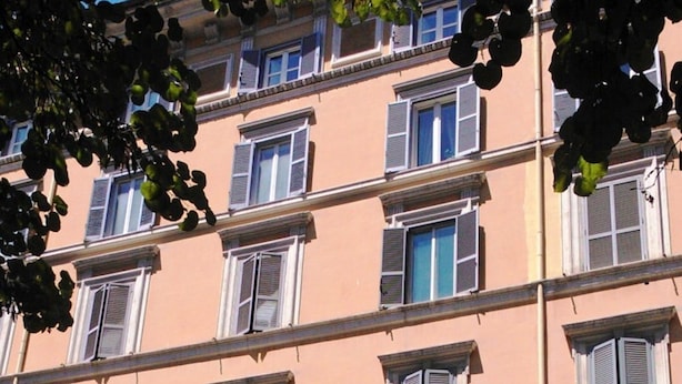A multi-story building with a row of windows and a balcony with railings.