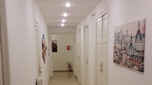 A hallway with white walls, a tiled floor, and doors on both sides.