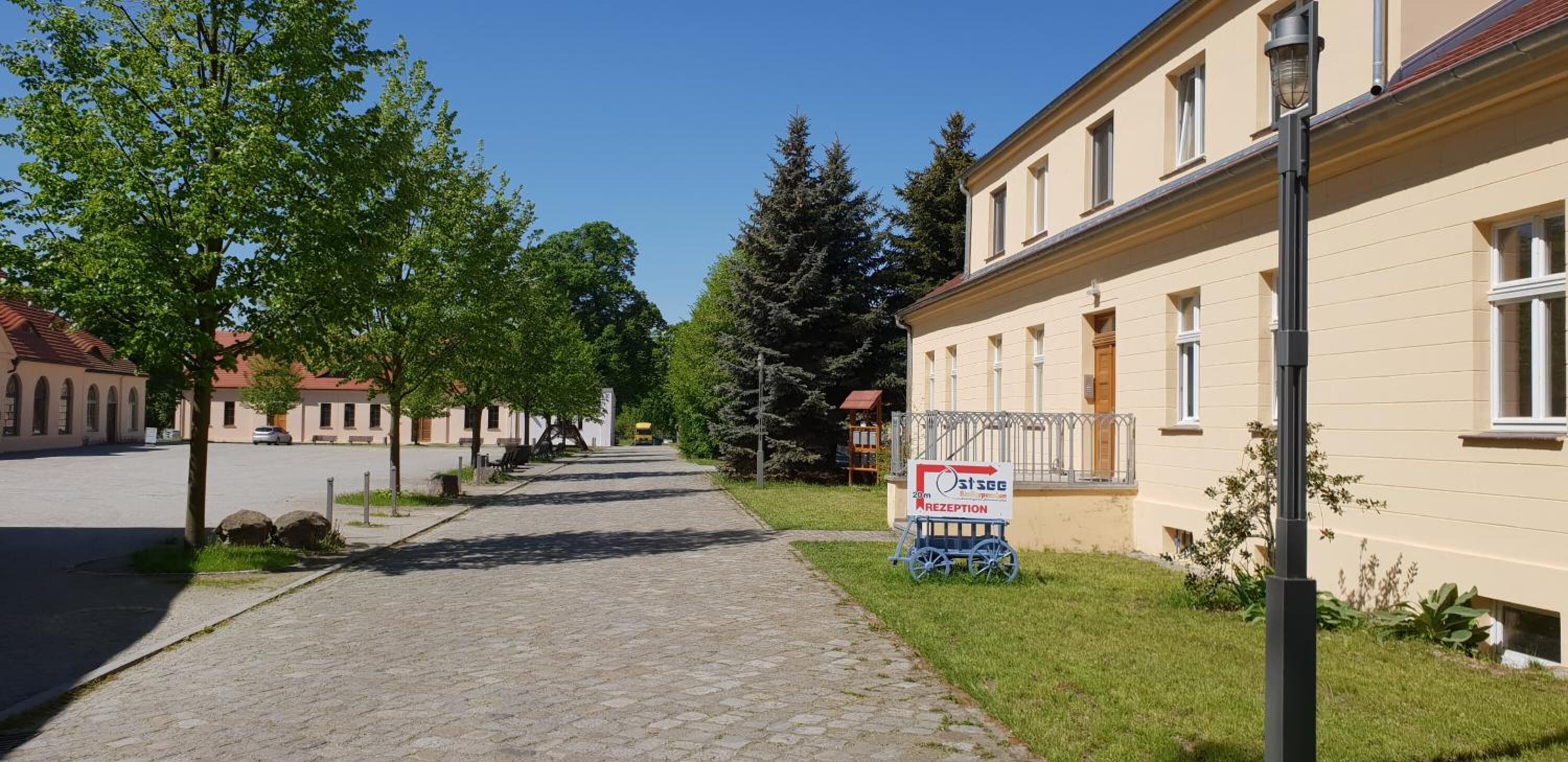 A street with a building on the right, a signboard, and a clear sky.