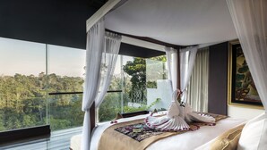 A bedroom with a large bed, white curtains, and a view of a forest. - Ayuterra Resort (Ubud)