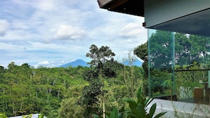 A modern building with large glass windows overlooking a lush green landscape and a mountain in the distance. - Ayuterra Resort (Ubud)