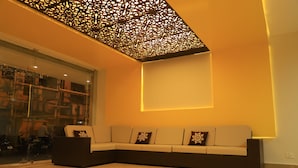 Un interior moderno con un sofá seccional, un techo decorativo y un amplio ventanal.