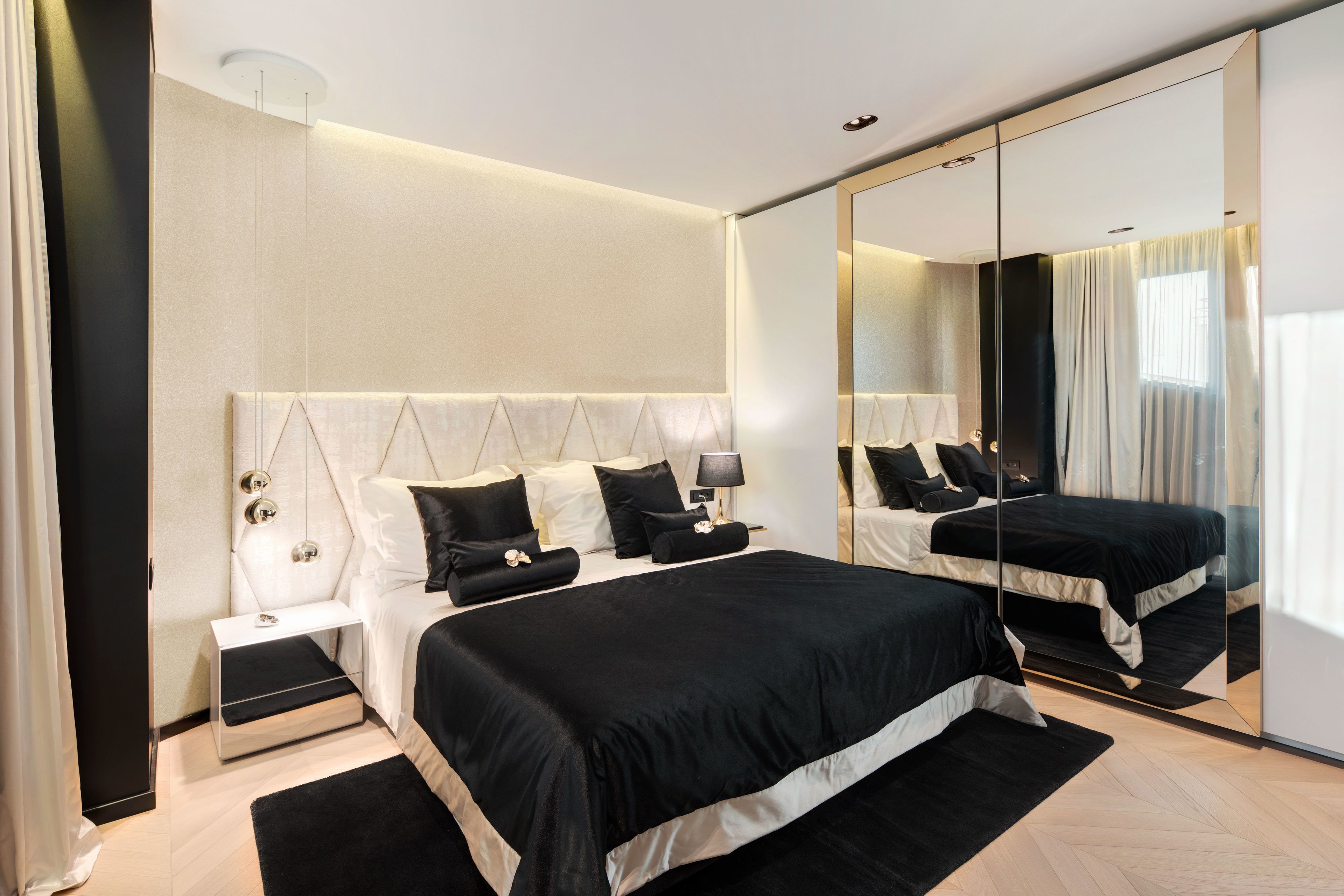 A modern bedroom with a large bed, a bedside table, a mirror, and a nightstand.
