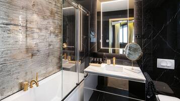 A modern bathroom with a glass-enclosed shower, a white vanity with a mirror, and black marble walls.