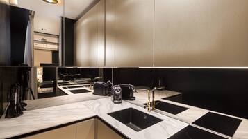 A modern kitchen with a marble countertop, black sink, and stainless steel appliances.
