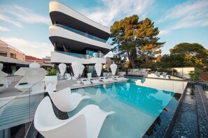 A modern building with a pool area, including white lounge chairs and a glass railing. - Posh Residence Luxury Suites (Split)