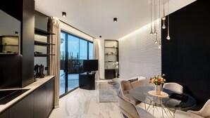 A modern kitchen with a large window, a dining area with a glass table, and a black accent wall. - Posh Residence Luxury Suites (Split)