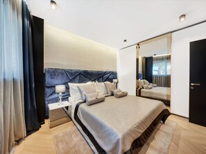 A modern bedroom with a large bed, a nightstand, a mirror, and a wardrobe. - Posh Residence Luxury Suites (Split)