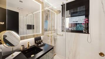 Un baño moderno con cabina de ducha de vidrio, un espejo grande y encimera negra.