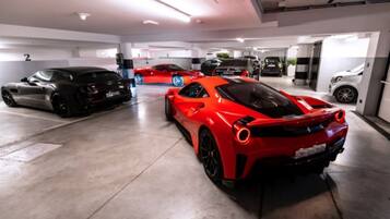 A parking garage with multiple cars, including a red sports car and a black sports car.