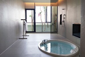 Un bany modern amb una banyera gran, una cabina de dutxa de vidre i vistes a la vegetació exterior.