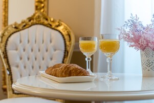 Un tavolo con un croissant, due bicchieri di succo d'arancia e un vaso con fiori rosa.