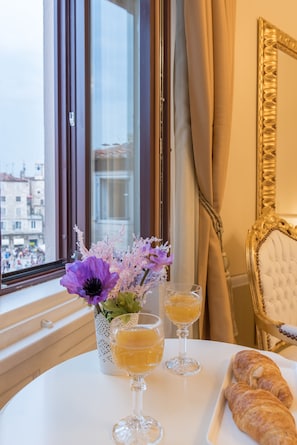 A table with a vase of flowers, two glasses of a yellow beverage, and a plate with croissants.