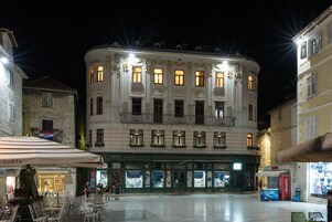 Um edifício histórico com um pátio central, apresentando um café com mesas ao ar livre e fachada visível.