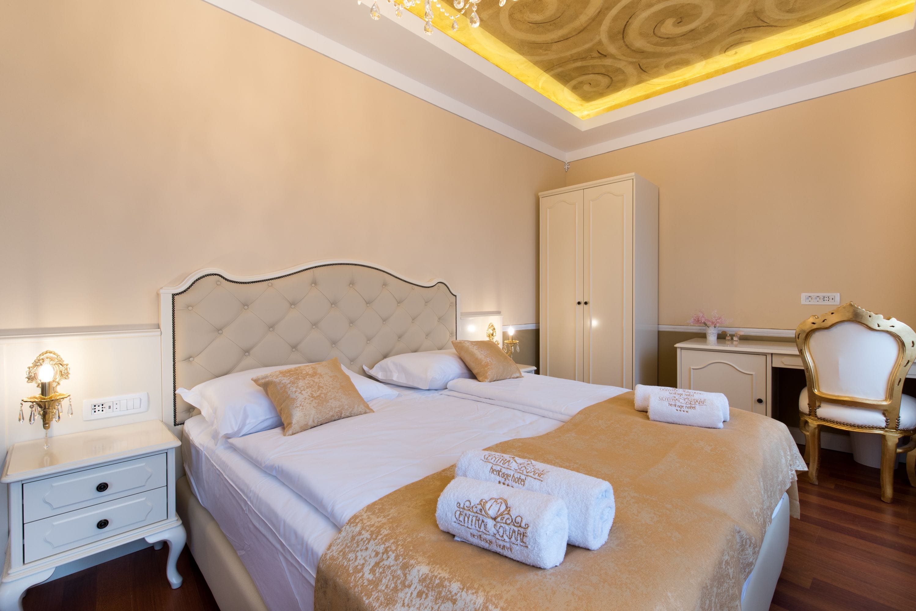 A neatly arranged bedroom with a large bed, a bedside table, a wardrobe, and a desk with a chair.
