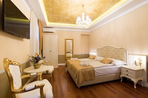 Habitación de hotel con una cama grande, televisor, candelabro y espejo.