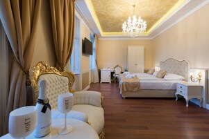Ein luxuriöses Schlafzimmer mit einem großen Bett, einer Sitzecke mit Chaiselongue, einem Schreibtisch und einem an der Wand befestigten Fernseher.