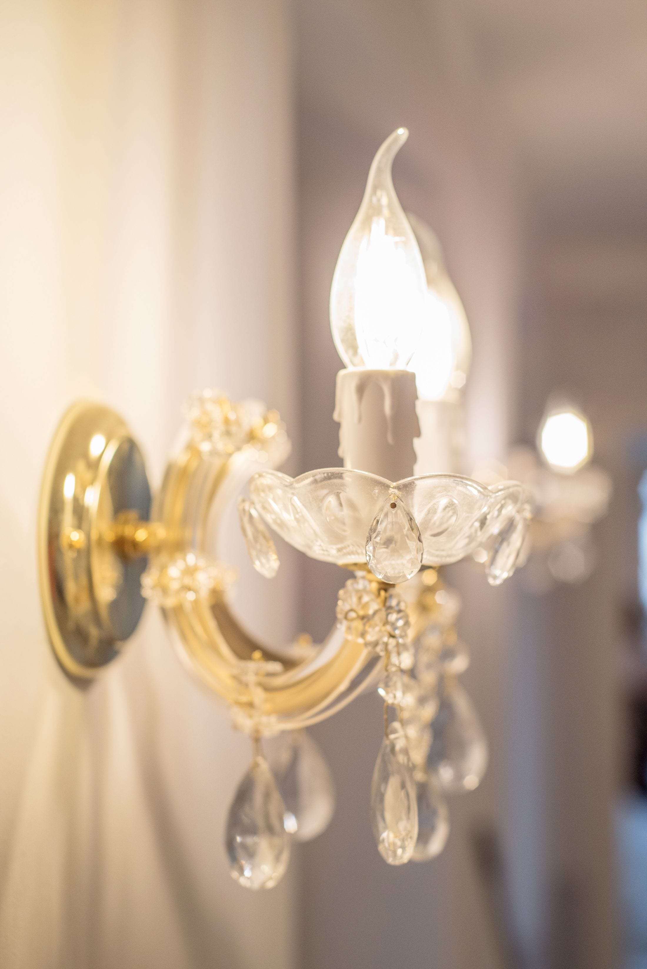 A close-up of a chandelier with crystal decorations and a lit bulb.
