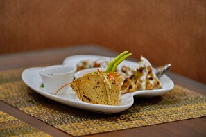 A plate of food with a small cup of sauce, placed on a woven placemat. - Brij Villa, Dalhousie - A Colonial Luxury Retreat (Dalhousie)