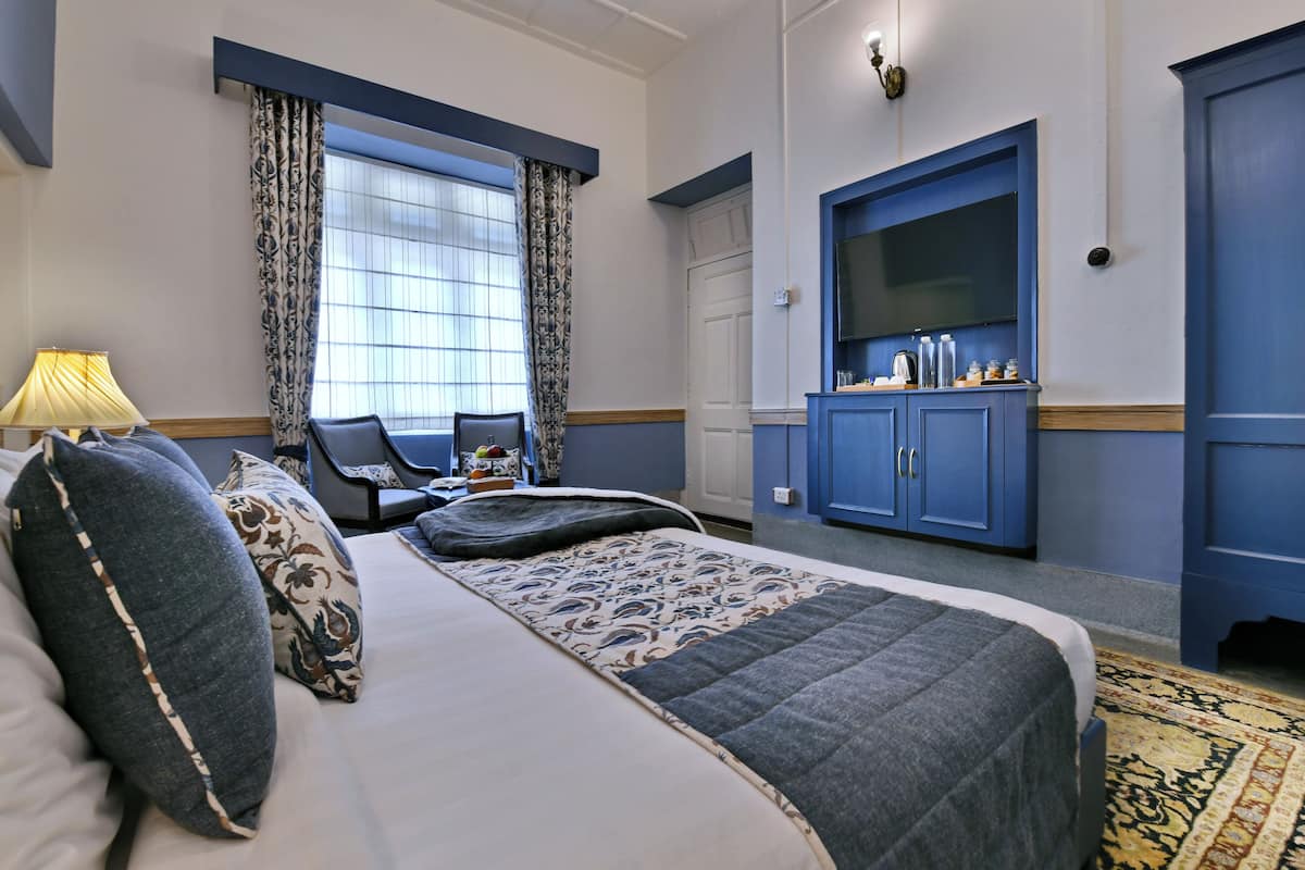 Una habitación de hotel con una cama, un escritorio, un armario y una ventana con cortinas.