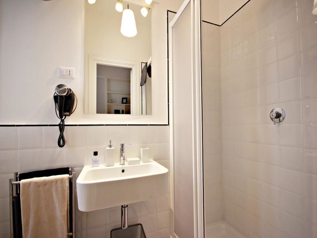 Ein Badezimmer mit Waschbecken, Spiegel, Föhn und Duschbereich.