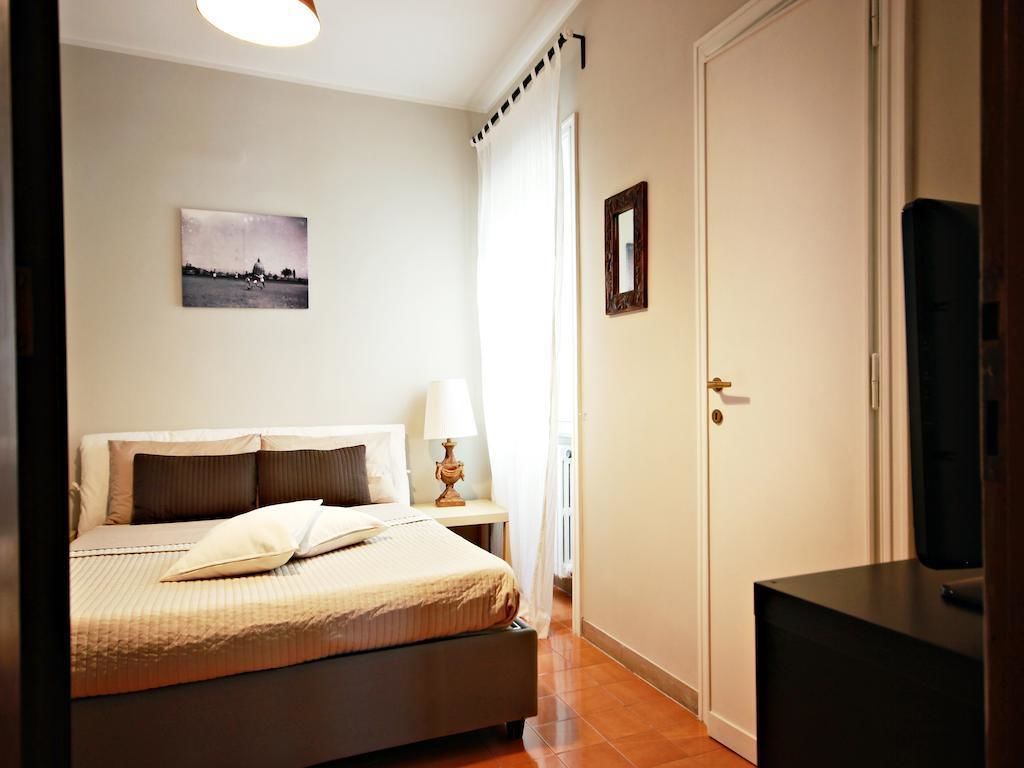 Une chambre à coucher avec un lit, une table de chevet, une lampe, un tableau au mur et une porte.
