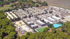 Vista aérea de um complexo residencial com vários edifícios de apartamentos, área de estacionamento e piscina.